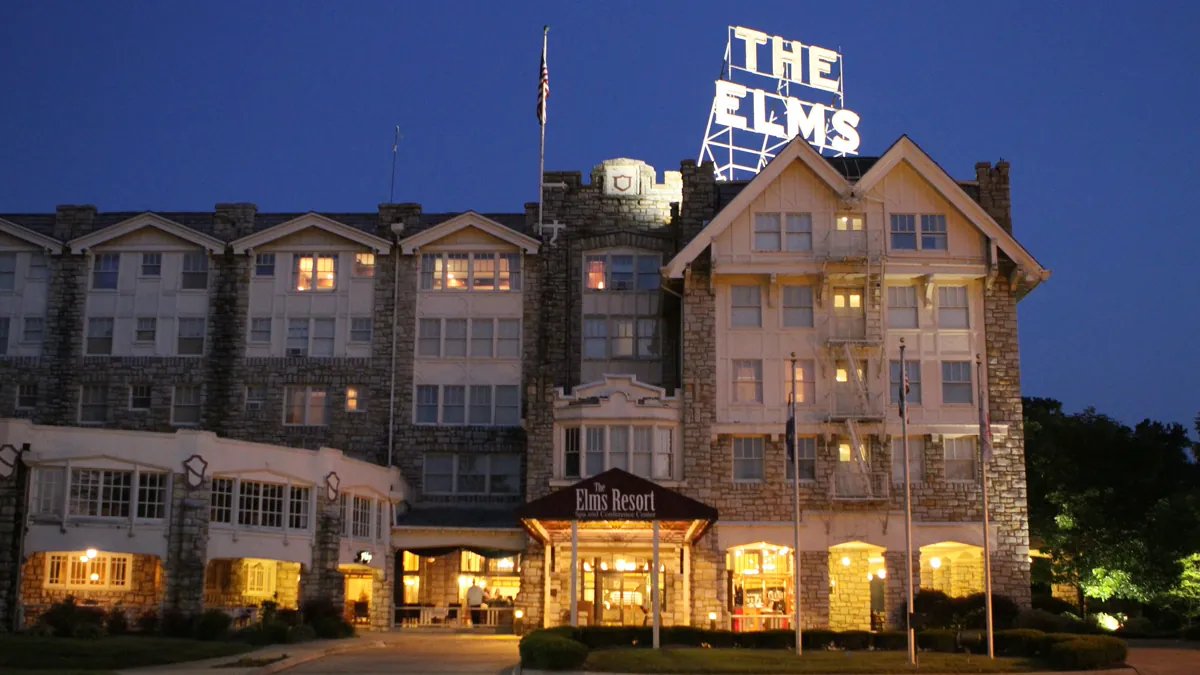 The Elms Hotel & Spa lit at dusk, its "THE ELMS" sign above the roofline